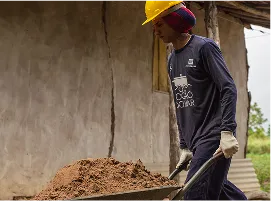 Homem empurrando um carrinho de mão cheio de areia